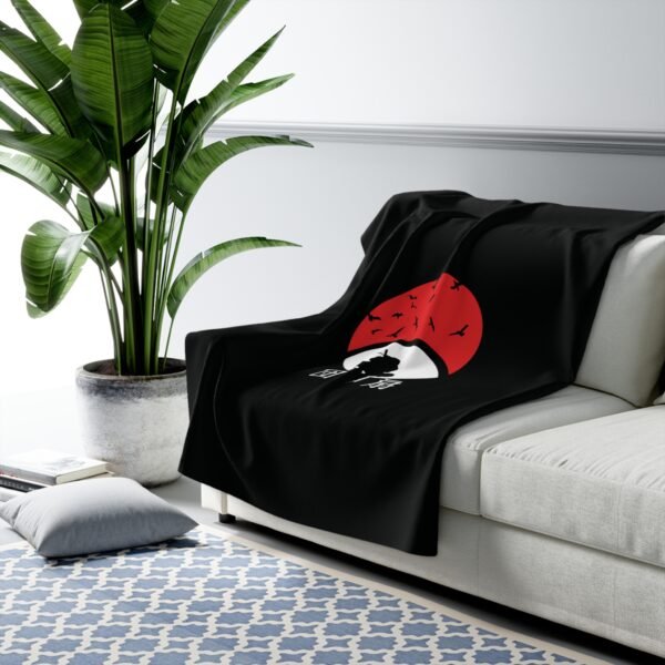 Black red blanket on white sofa with plant nearby.