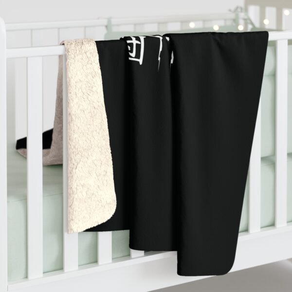 Black blanket with white lining on crib rail.