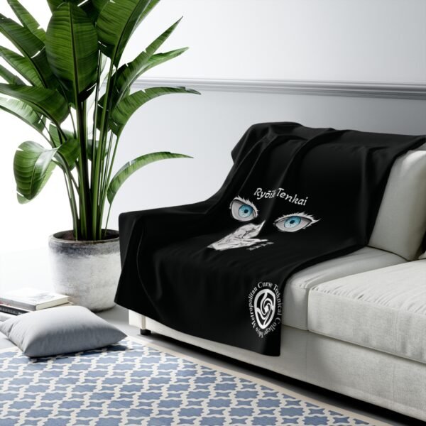 Black throw blanket with eye design on sofa.